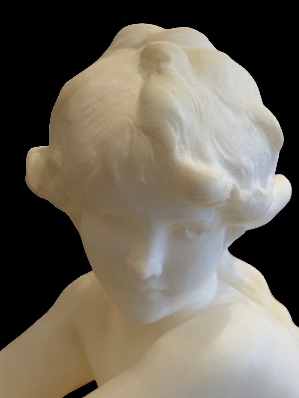 A carved off-white alabaster sculpture depicting a semi-clad reclining woman resting on a chaise longue set on a rectangular plinth. View II