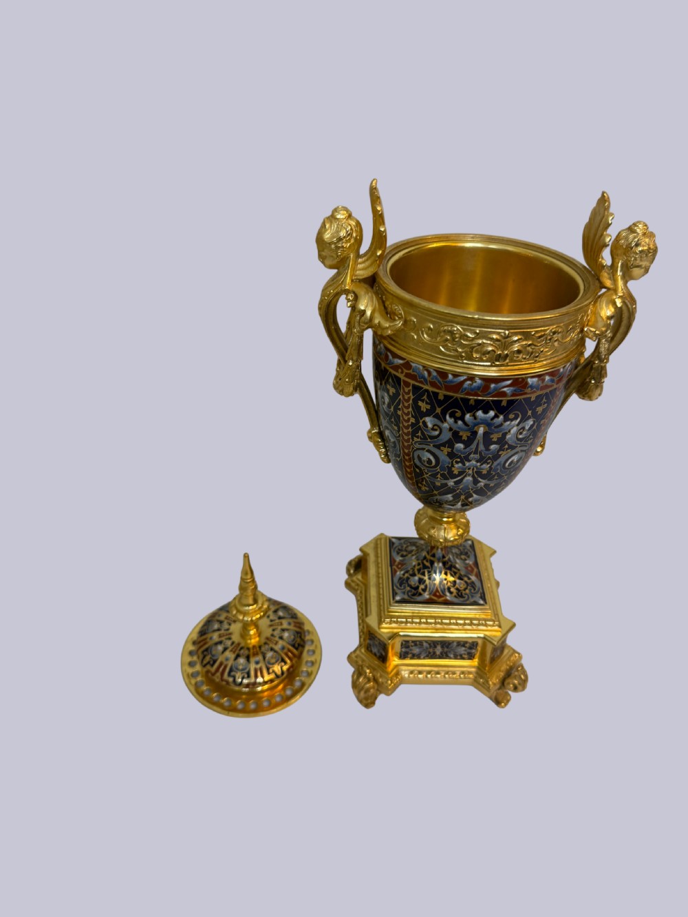 A 19th-century French lidded urn crafted from gilt bronze featuring blue and red champleve enamel detailing with figural handles and a finial lid. View IV