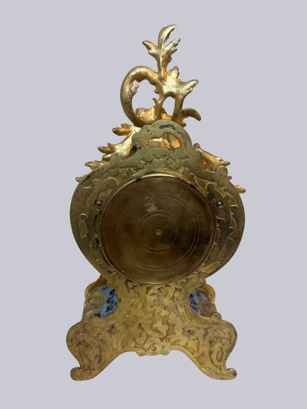 An ornate French Rococo Revival mantel clock featuring gilt bronze scrollwork, light blue champleve enamel patterns, and a white enamel dial with floral decoration, shown with a winding key. View VI