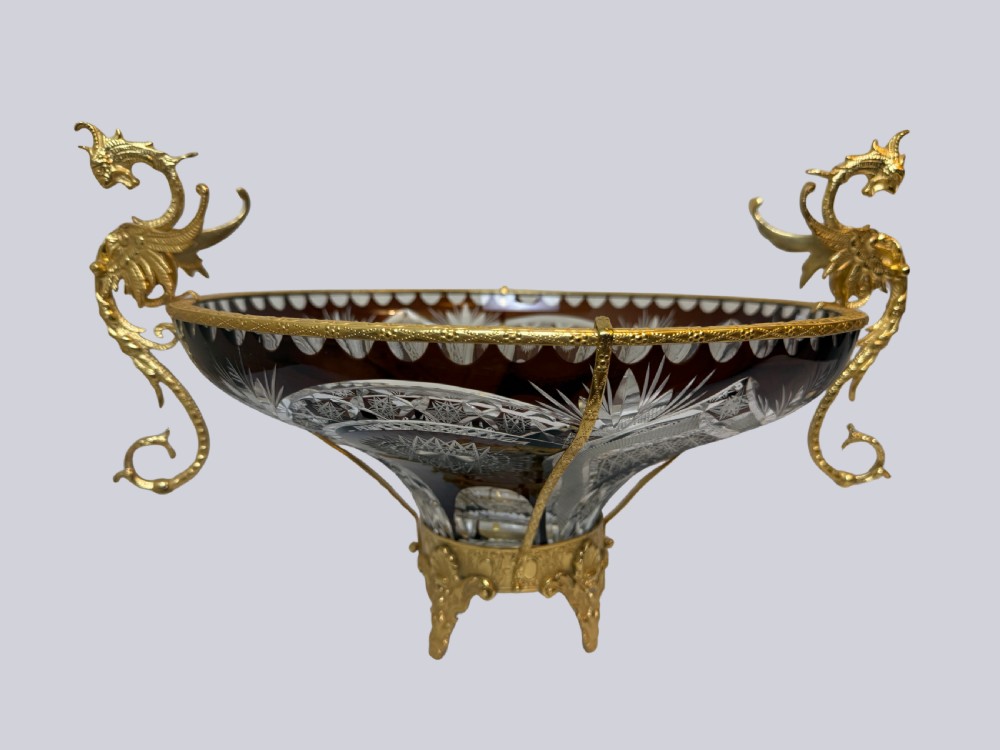 A deep red and clear cut glass bowl featuring gilt bronze dragon handles and a footed metal base. View III