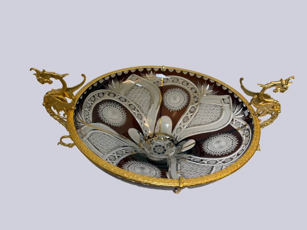 A deep red and clear cut glass bowl featuring gilt bronze dragon handles and a footed metal base. View IV