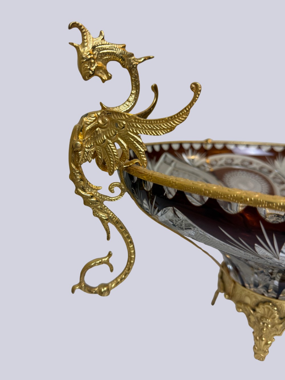 A deep red and clear cut glass bowl featuring gilt bronze dragon handles and a footed metal base. View V