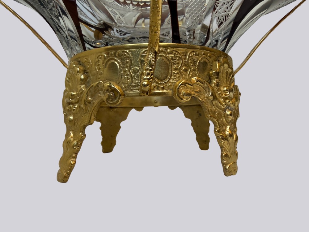 A deep red and clear cut glass bowl featuring gilt bronze dragon handles and a footed metal base. View VI