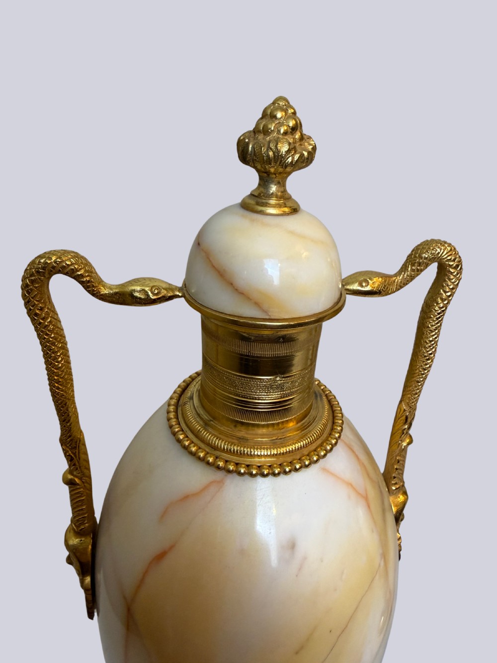 A pair of 19th-century ovoid white onyx urns featuring gilt bronze serpent handles, finials, and square pedestals. View III
