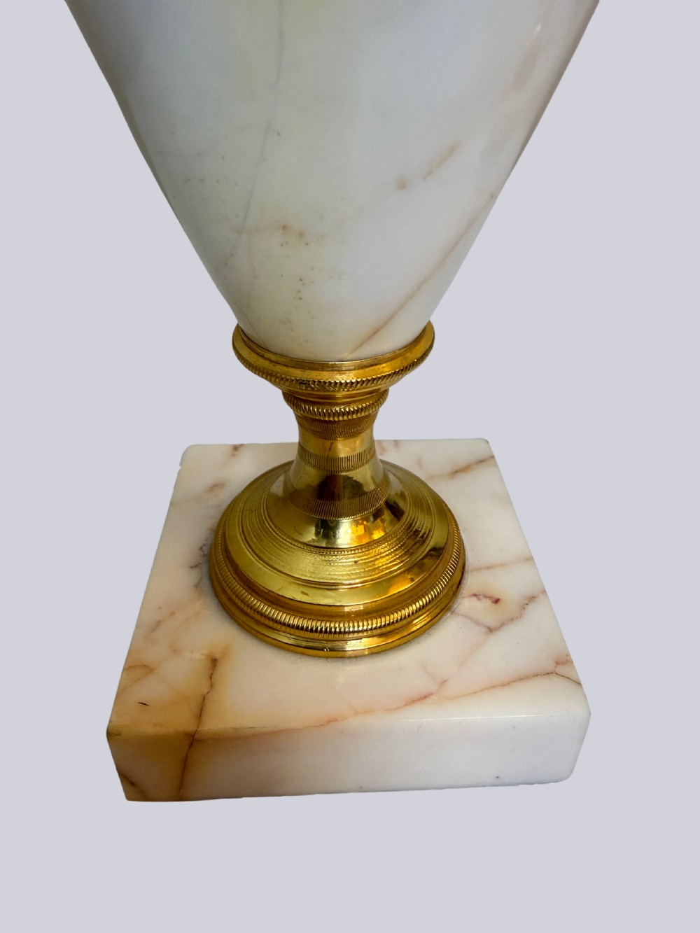 A pair of 19th-century ovoid white onyx urns featuring gilt bronze serpent handles, finials, and square pedestals. View V