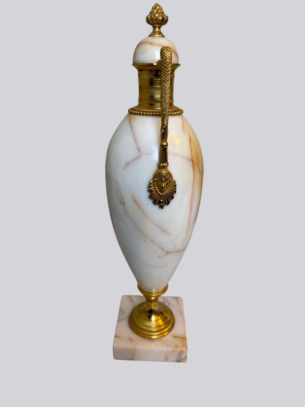 A pair of 19th-century ovoid white onyx urns featuring gilt bronze serpent handles, finials, and square pedestals. View VI