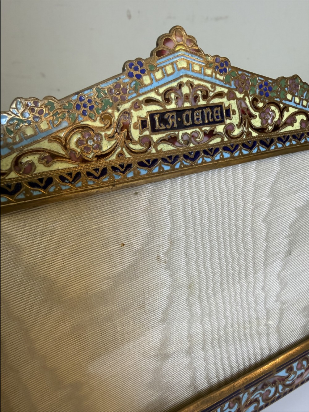 A 19th-century French gilt bronze and champleve enamel picture frame resting alongside a matching hand mirror with colourful floral motifs. View IV