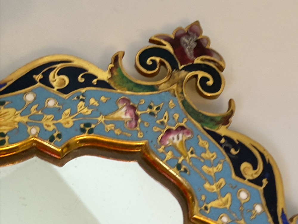 A 19th-century French gilt bronze and champleve enamel picture frame resting alongside a matching hand mirror with colourful floral motifs. View VIII