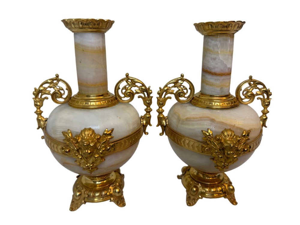 A pair of 19th-century French vases constructed from cream white veined onyx with ornate gilt bronze handles, winged cherub mounts, and footed bases.