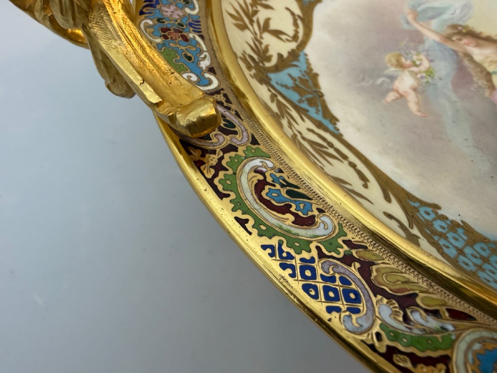 A circular 19th-century French porcelain centrepiece with hand-painted classical figures framed by colourful champleve enamel and twin gilt bronze handles. View V