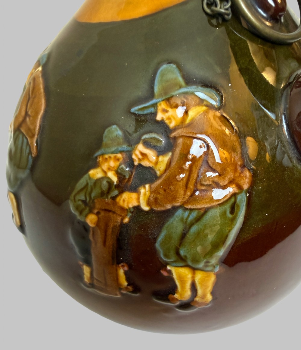 A brown and ochre glazed ceramic whisky flask featuring a raised relief figure of a golfer with an attached cork stopper on a metal chain. View IV