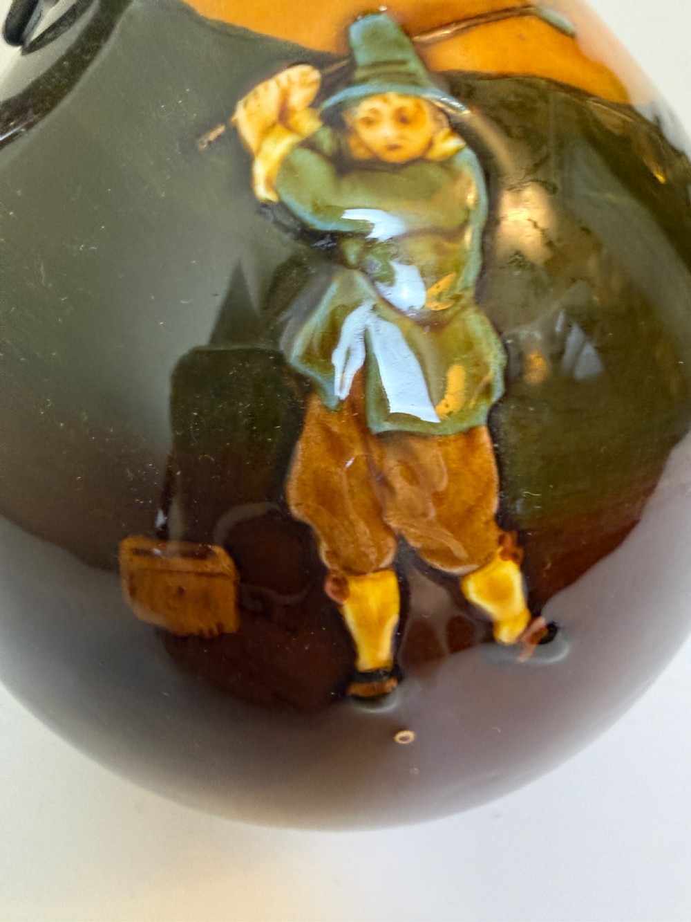 A brown and ochre glazed ceramic whisky flask featuring a raised relief figure of a golfer with an attached cork stopper on a metal chain. View V