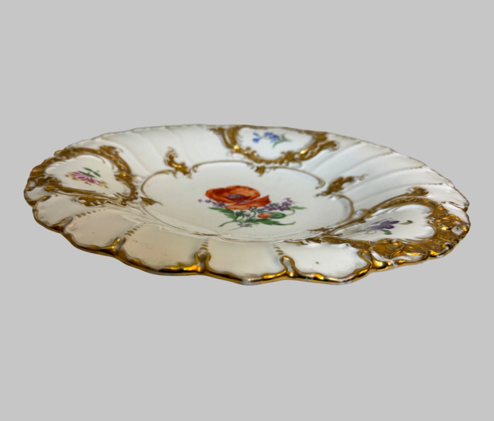 A white scalloped porcelain dish featuring hand-painted central botanical flowers surrounded by gilded Rococo cartouches containing smaller floral sprays. View II