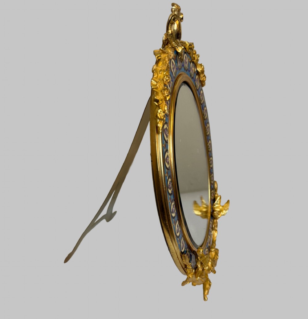 An oval late nineteenth-century French table mirror featuring a gilt bronze frame with blue champleve enamel scrollwork and ornate cast feet. View II