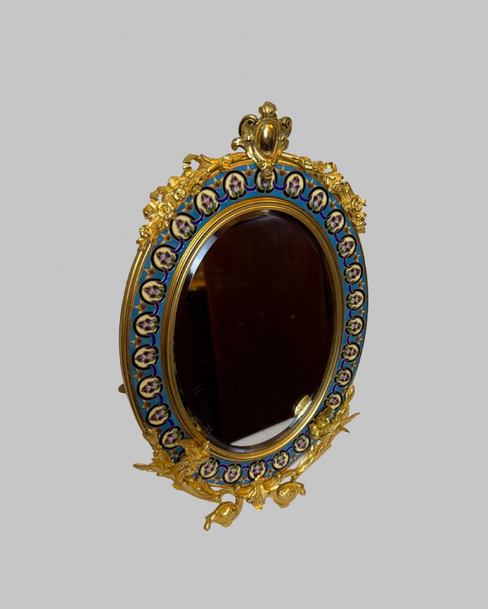 An oval late nineteenth-century French table mirror featuring a gilt bronze frame with blue champleve enamel scrollwork and ornate cast feet. View IV