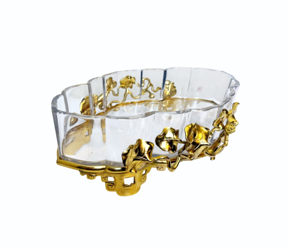 An oval crystal bowl set in an Art Nouveau gilt bronze frame adorned with sculpted leaves and organic vines.