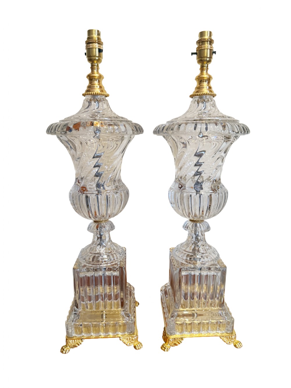 A pair of 19th-century French clear cut-crystal urn-form table lamps featuring spiral fluting, square pedestals, and gilt-metal claw feet.
