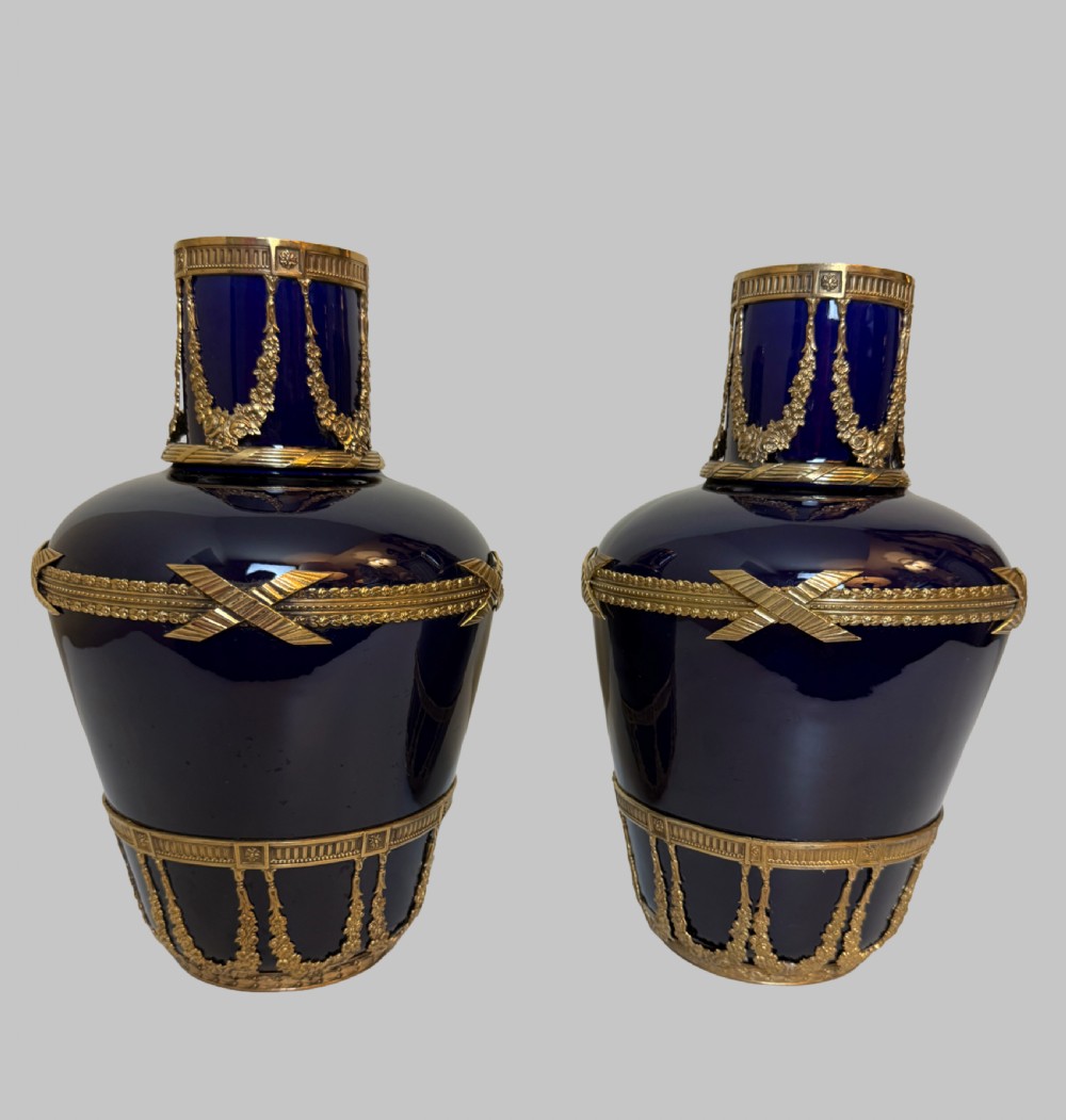 A pair of cobalt blue glass vases featuring ornate gilt bronze floral garlands, ribbon details, and metal rim mounts. View II