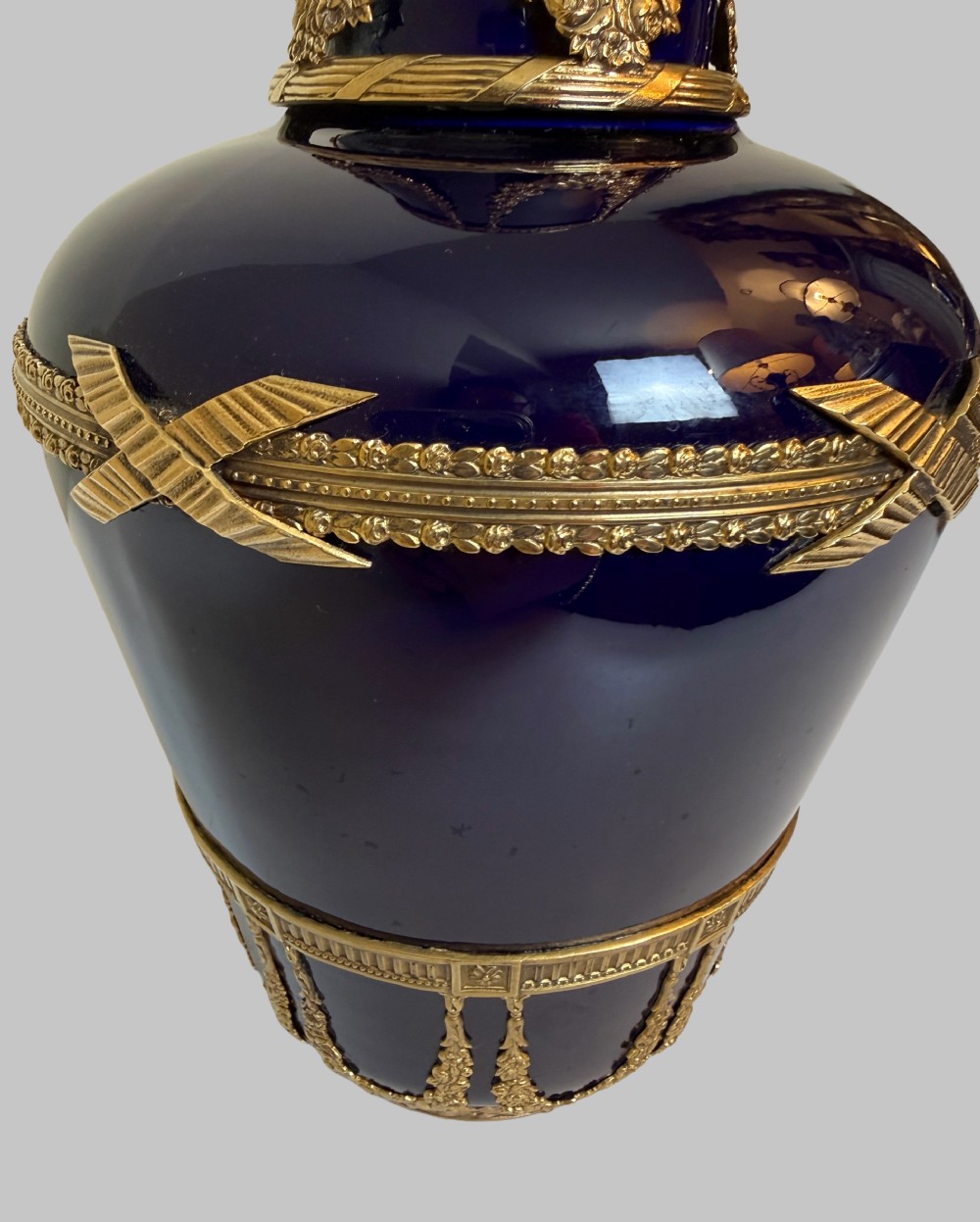 A pair of cobalt blue glass vases featuring ornate gilt bronze floral garlands, ribbon details, and metal rim mounts. View V
