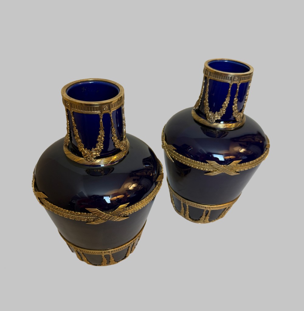 A pair of cobalt blue glass vases featuring ornate gilt bronze floral garlands, ribbon details, and metal rim mounts. View VII