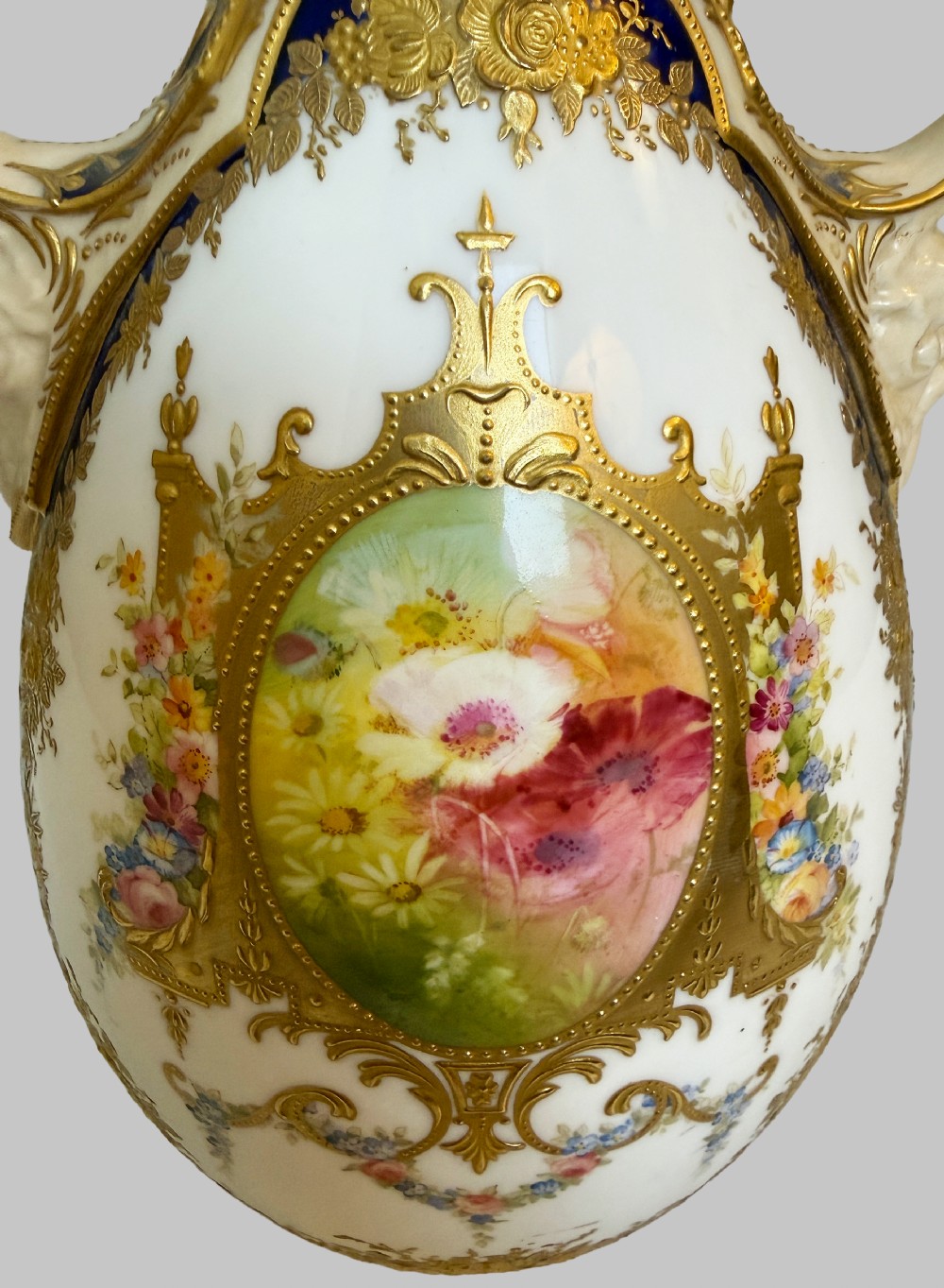 An antique Royal Doulton porcelain vase featuring cobalt blue and white glazes, heavy gilt scrolling, scroll handles with mask terminals, and a central hand-painted floral panel. View III