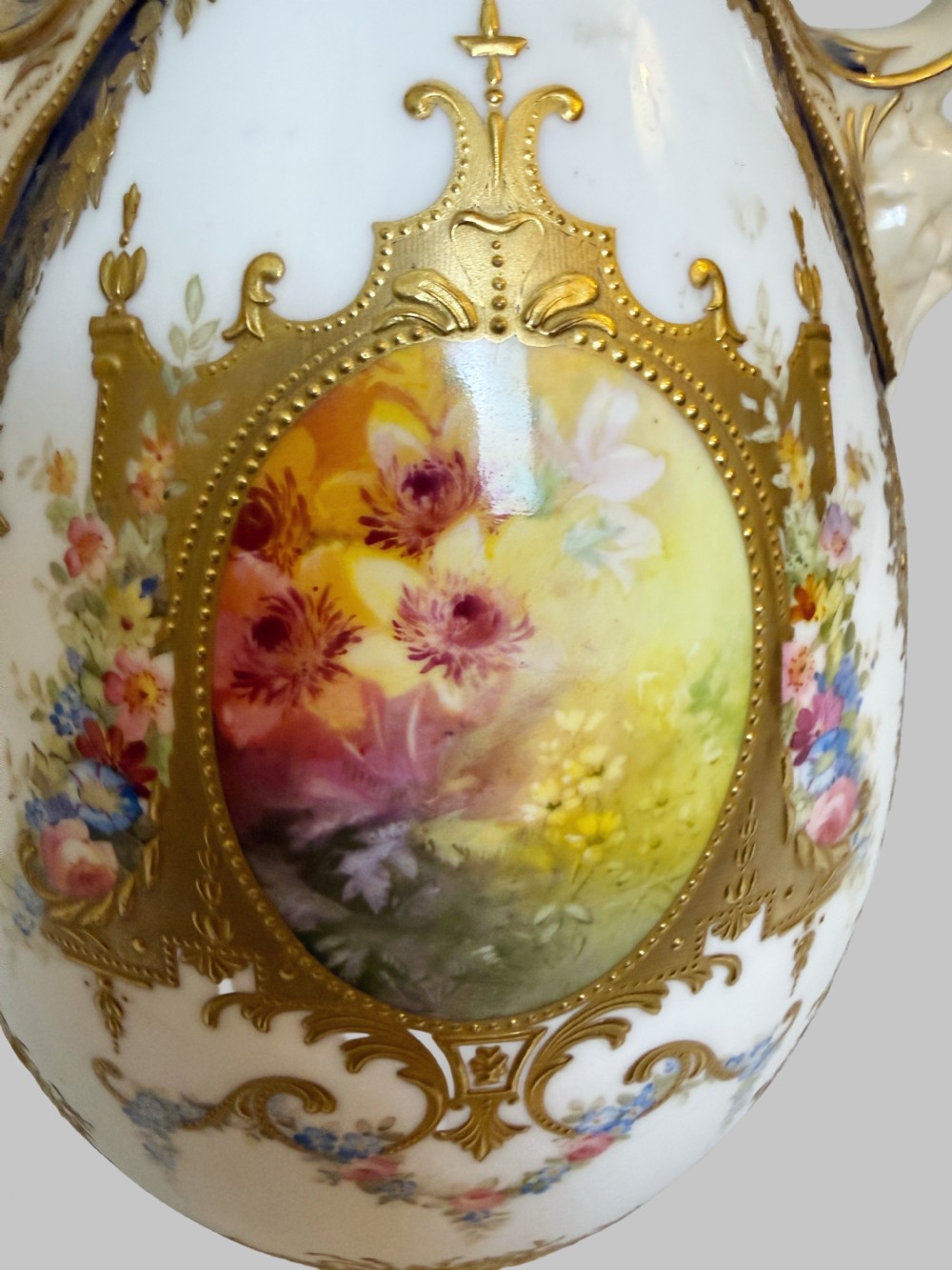 An antique Royal Doulton porcelain vase featuring cobalt blue and white glazes, heavy gilt scrolling, scroll handles with mask terminals, and a central hand-painted floral panel. View VI