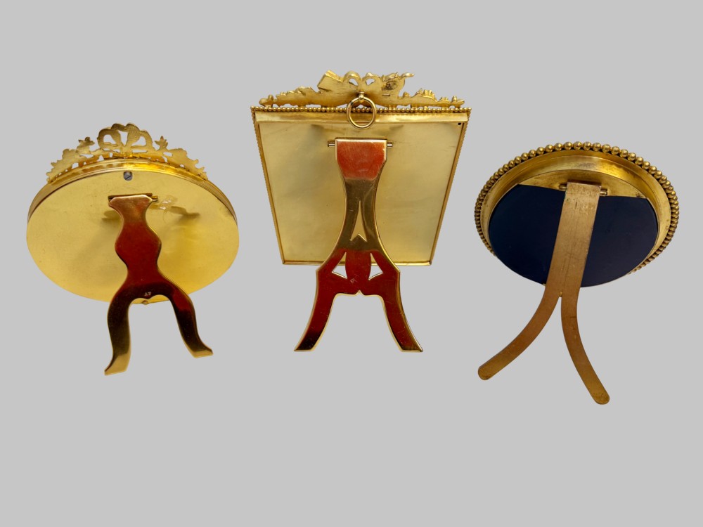 A trio of antique French gilt bronze picture frames featuring ribbon crests, beaded borders, and an onyx panel mount. View II
