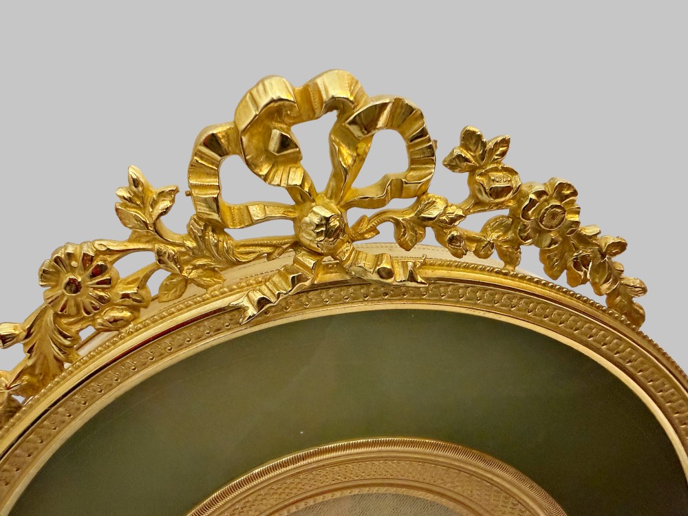 A trio of antique French gilt bronze picture frames featuring ribbon crests, beaded borders, and an onyx panel mount. View V