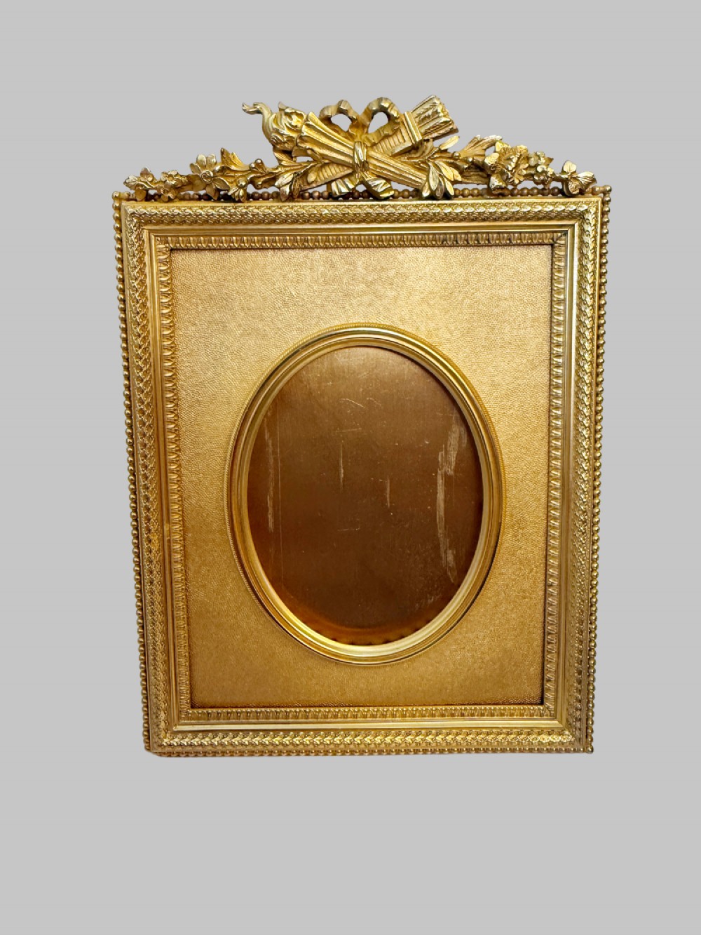 A trio of antique French gilt bronze picture frames featuring ribbon crests, beaded borders, and an onyx panel mount. View VI