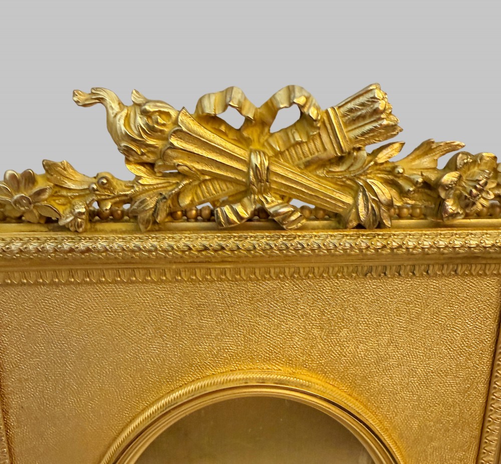 A trio of antique French gilt bronze picture frames featuring ribbon crests, beaded borders, and an onyx panel mount. View VII