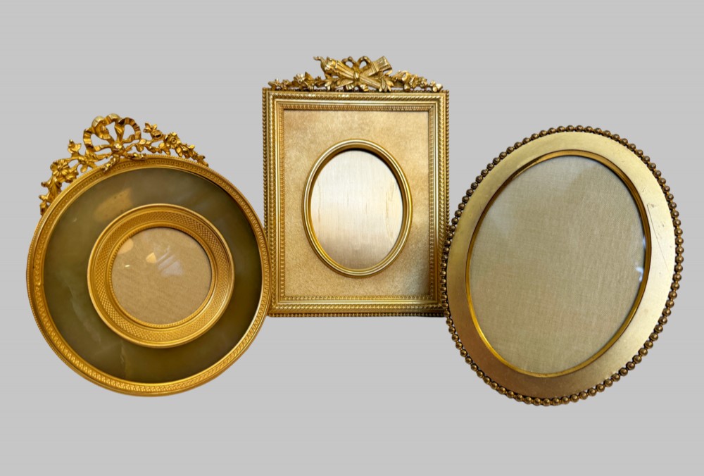 A trio of antique French gilt bronze picture frames featuring ribbon crests, beaded borders, and an onyx panel mount. View VIII
