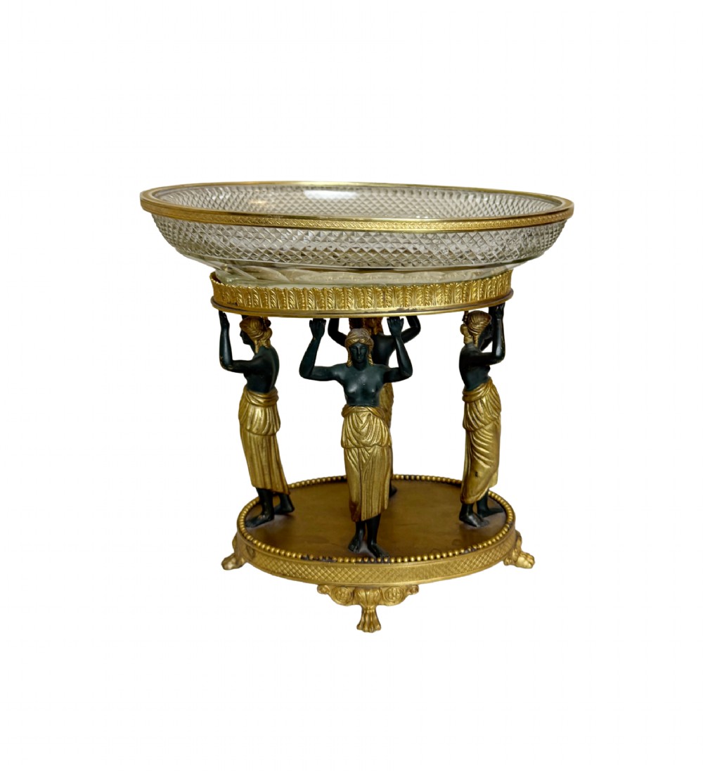 An early 19th-century cut-crystal bowl supported by four patinated bronze female caryatids with gilt drapery, set upon a circular gilt bronze base.