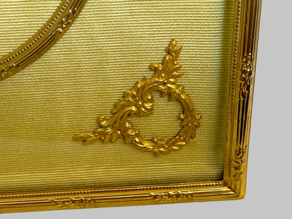 A 19th-century rectangular French gilt bronze frame featuring two circular photograph openings set against a cream silk background, adorned with a floral crest and ribbon mounts. View V