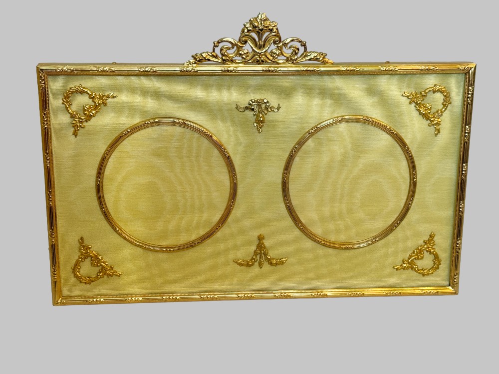 A 19th-century rectangular French gilt bronze frame featuring two circular photograph openings set against a cream silk background, adorned with a floral crest and ribbon mounts. View VIII