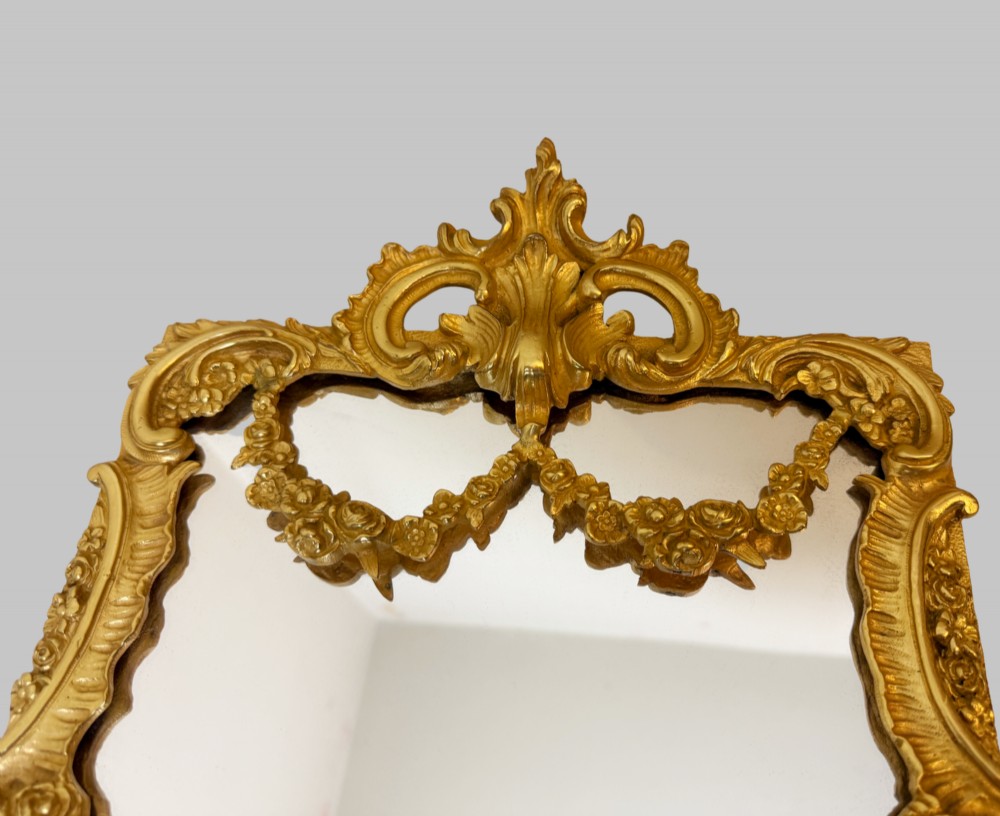 An ornate gold gilt bronze table mirror featuring Rococo scrollwork, floral garlands, and a carved crest motif. View II