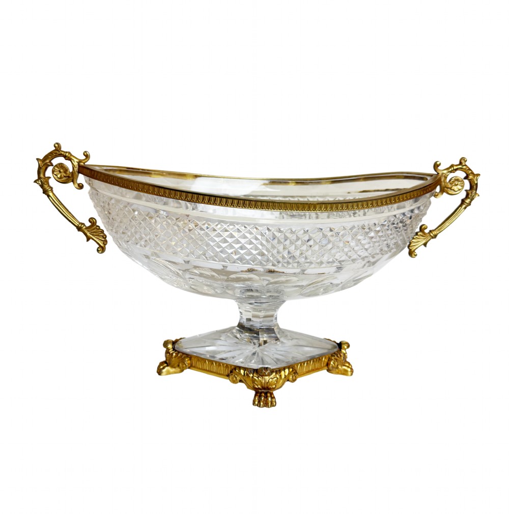 A late 19th-century French boat-shaped cut crystal centrepiece bowl set within gilded bronze mounts with dual scroll handles and a footed square base.
