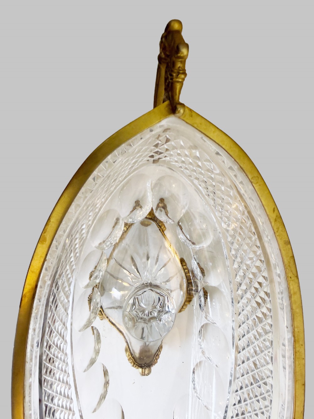 A late 19th-century French boat-shaped cut crystal centrepiece bowl set within gilded bronze mounts with dual scroll handles and a footed square base. View VII