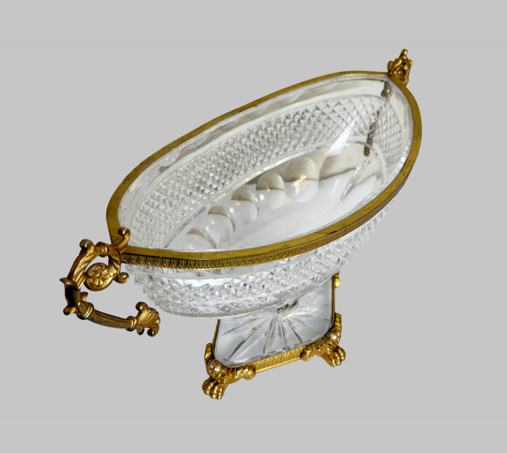 A late 19th-century French boat-shaped cut crystal centrepiece bowl set within gilded bronze mounts with dual scroll handles and a footed square base. View IX