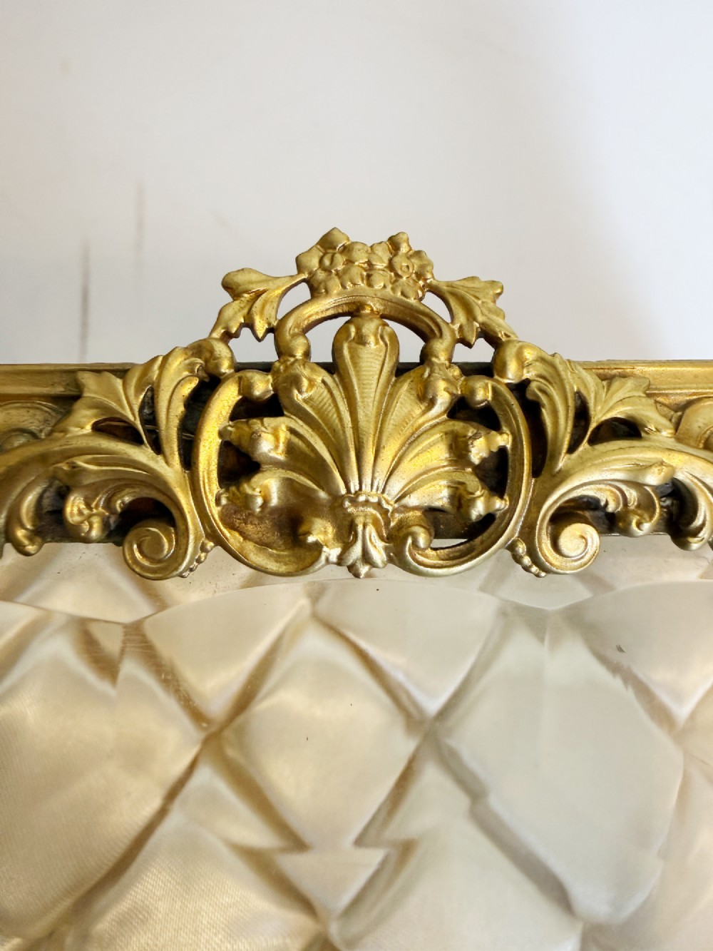 An antique rectangular bevelled crystal glass jewellery box featuring an ornate gilt bronze frame with decorative corner mounts and a button-tufted silk cushion interior. View IV