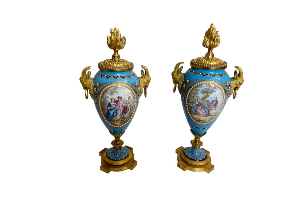 A pair of turquoise blue enamelled cassolette urns featuring gilt-bronze ram head handles, flame finials, and painted romantic pastoral vignettes.