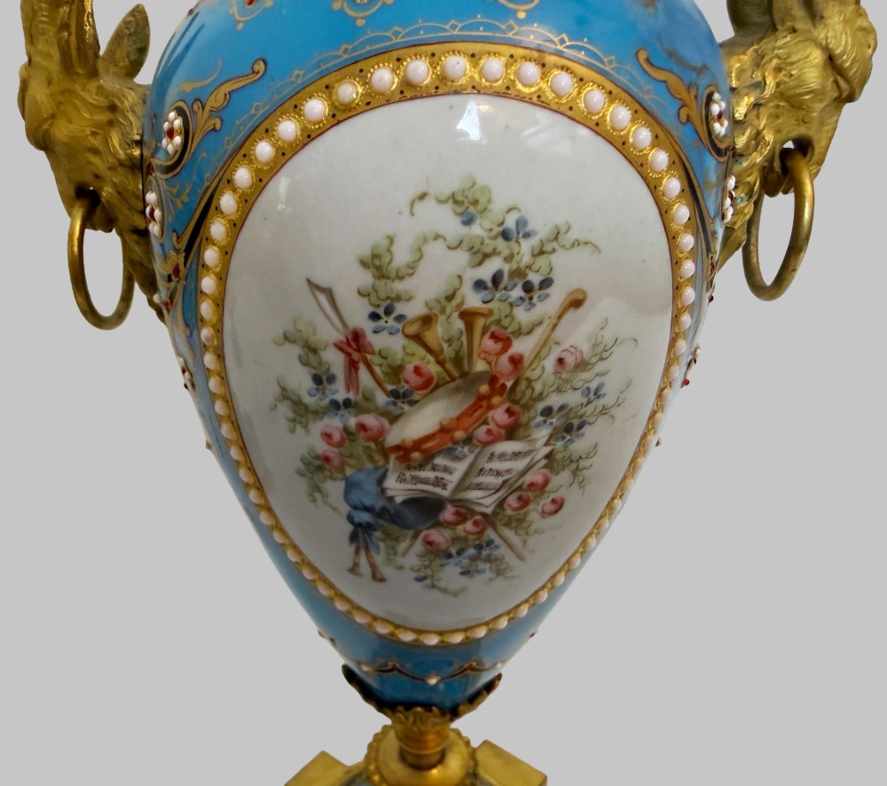 A pair of turquoise blue enamelled cassolette urns featuring gilt-bronze ram head handles, flame finials, and painted romantic pastoral vignettes. View II