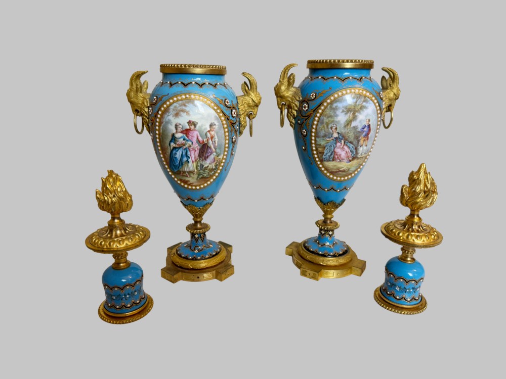 A pair of turquoise blue enamelled cassolette urns featuring gilt-bronze ram head handles, flame finials, and painted romantic pastoral vignettes. View V