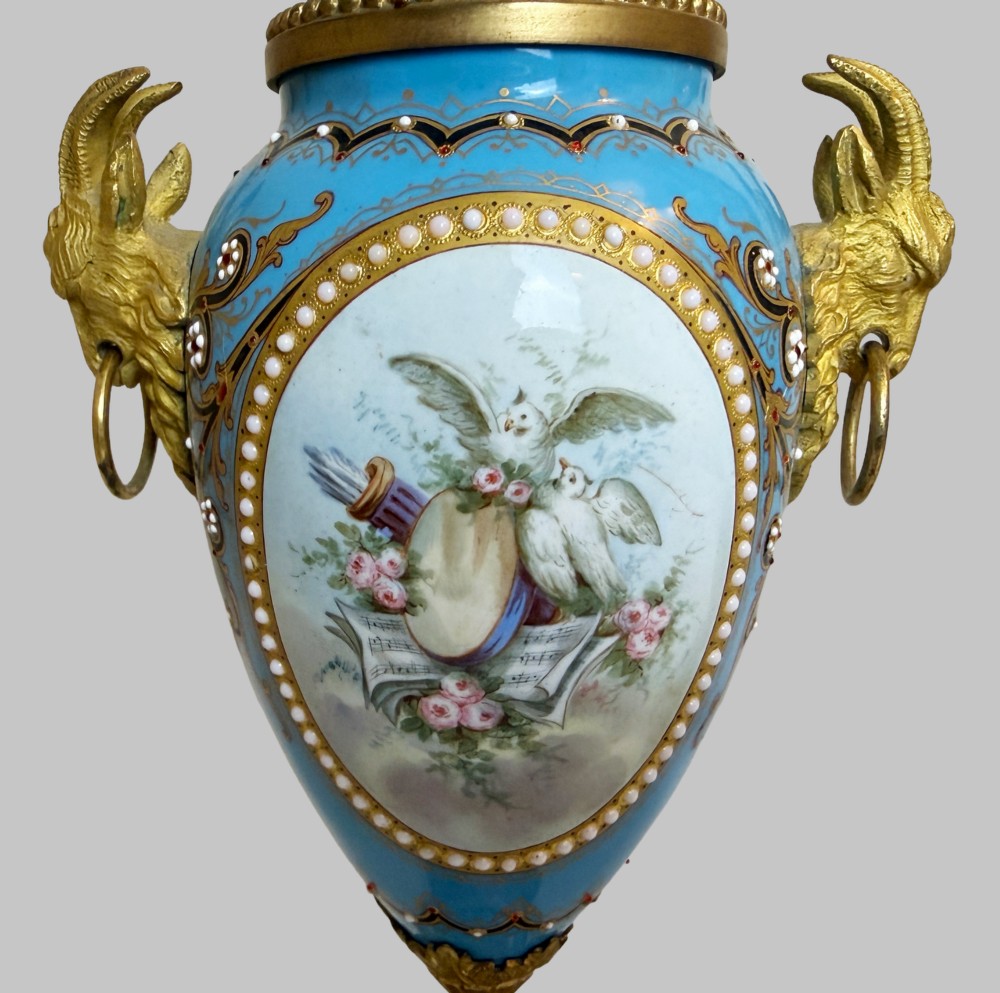 A pair of turquoise blue enamelled cassolette urns featuring gilt-bronze ram head handles, flame finials, and painted romantic pastoral vignettes. View VIII