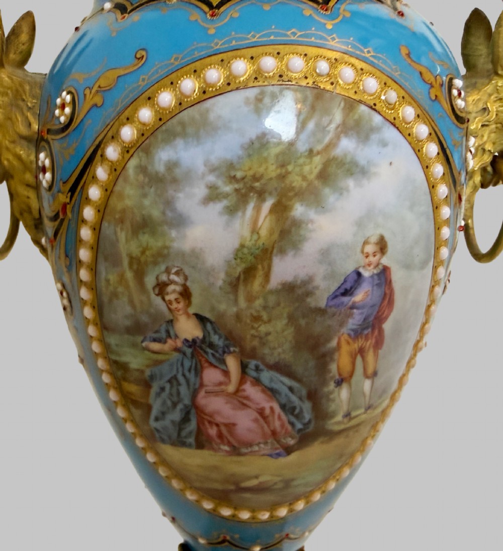 A pair of turquoise blue enamelled cassolette urns featuring gilt-bronze ram head handles, flame finials, and painted romantic pastoral vignettes. View IX