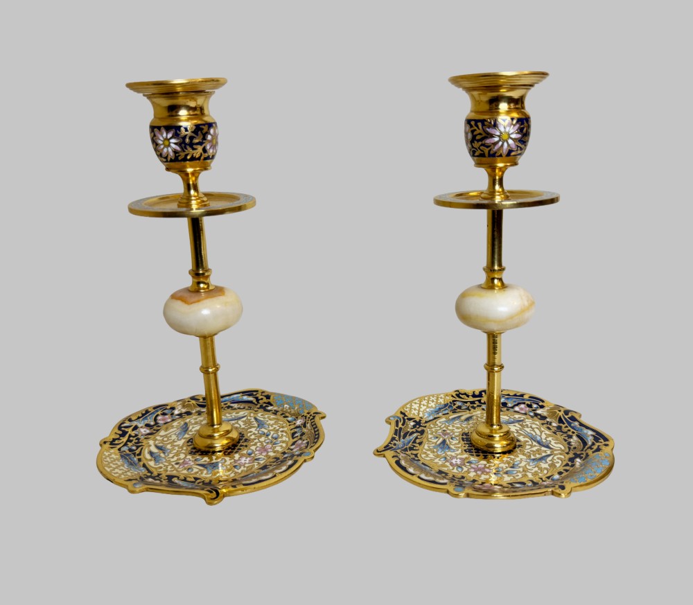 A pair of 19th-century gilt bronze candlesticks featuring floral champleve enamel decoration, central onyx knops, and shaped wide bases. View IV