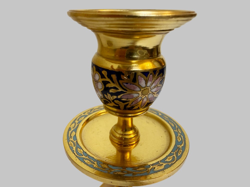 A pair of 19th-century gilt bronze candlesticks featuring floral champleve enamel decoration, central onyx knops, and shaped wide bases. View V