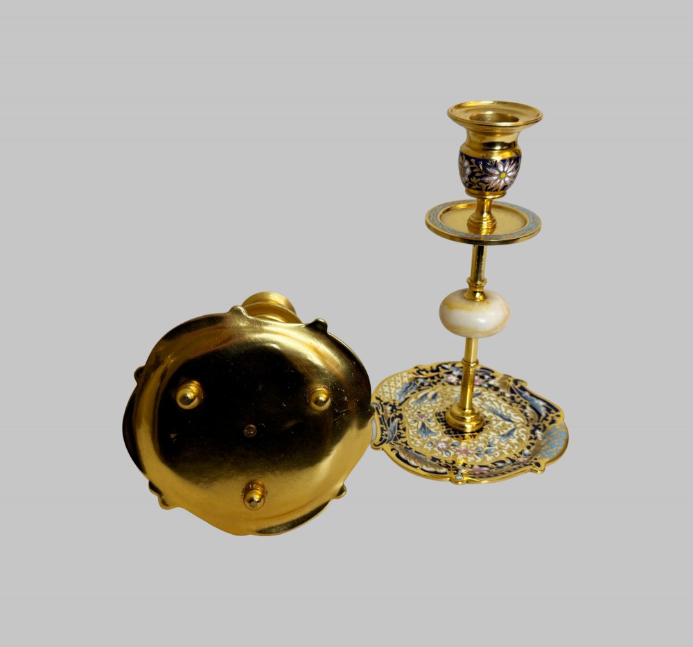 A pair of 19th-century gilt bronze candlesticks featuring floral champleve enamel decoration, central onyx knops, and shaped wide bases. View VI