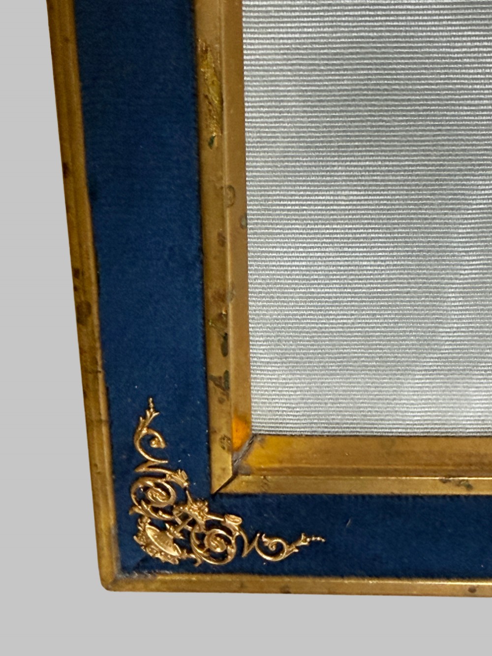 A rectangular gilt bronze picture frame featuring a blue velvet border, ornate corner mounts, and an elaborate floral crest at the top. View VIII
