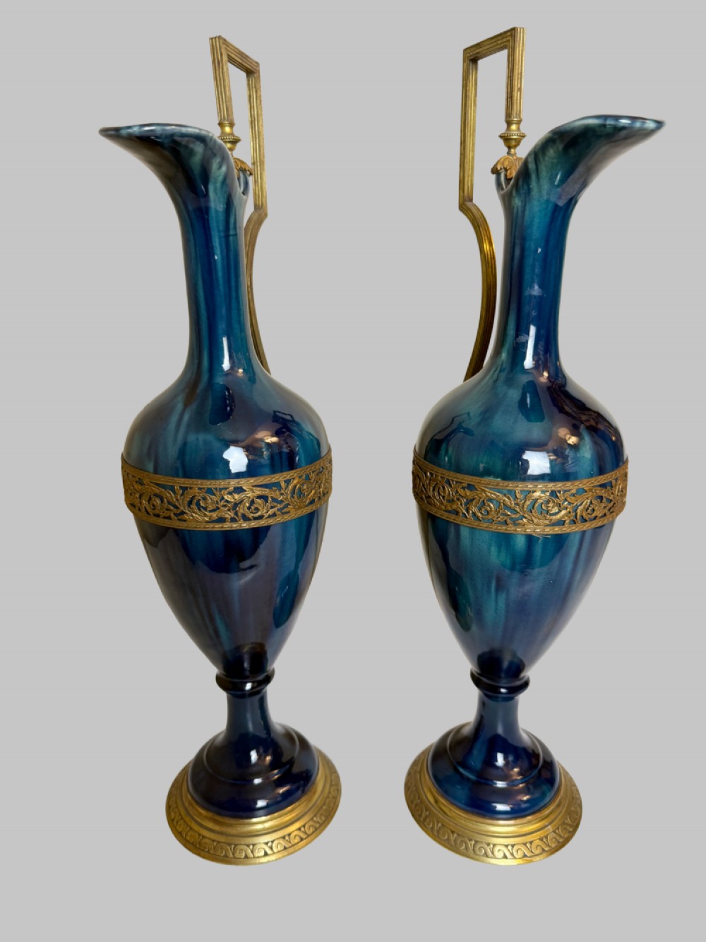A pair of slender blue porcelain ewers featuring decorative gilt bronze mounts, angular handles, and flared spouts. View II