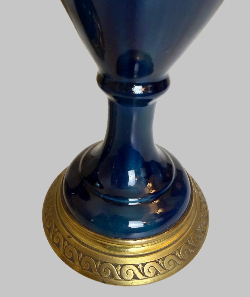 A pair of slender blue porcelain ewers featuring decorative gilt bronze mounts, angular handles, and flared spouts. View V